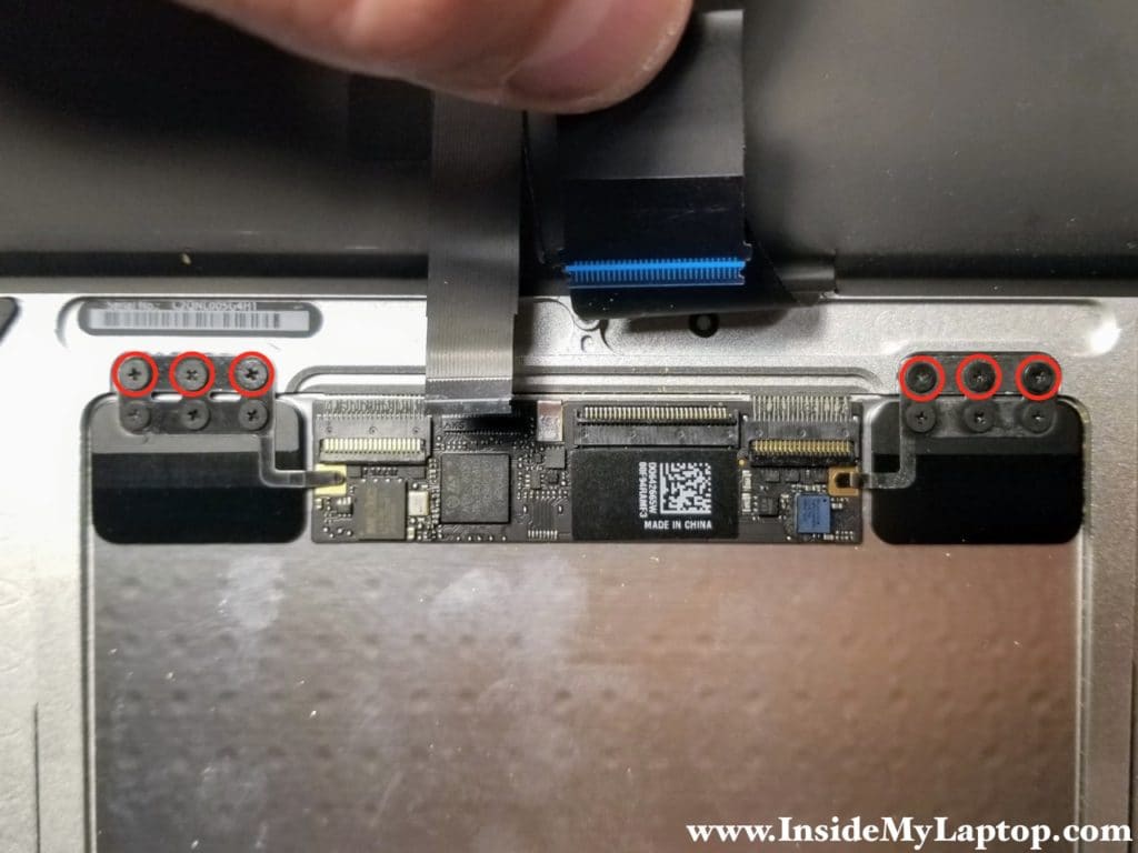 Remove six screws securing trackpad brackets