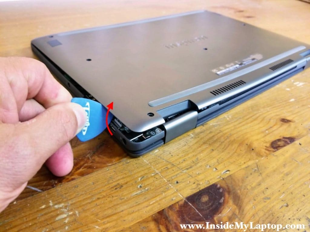 Using a thin case opener tool start separating the base cover from the palmrest assembly.