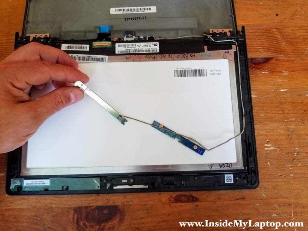 Carefully separate the webcam and the blue board from the bezel and unroute the cable from the guided path on the right side.