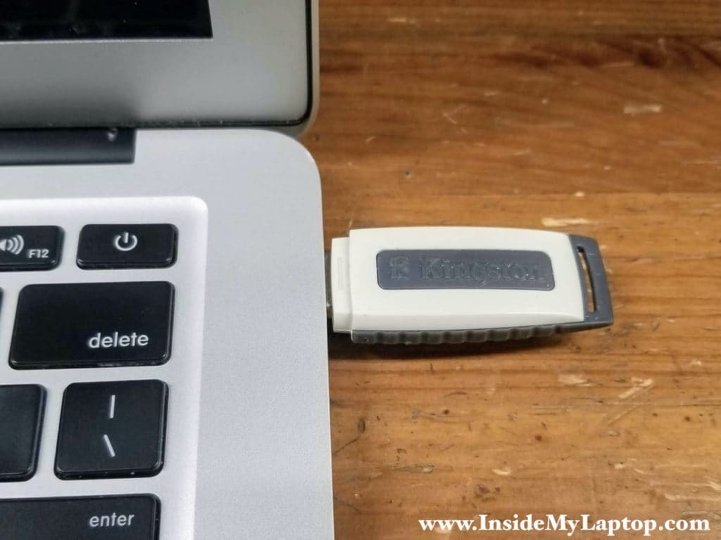 The flash drive connector fits all the way in and the plastic body of the drive is almost touching the laptop frame.