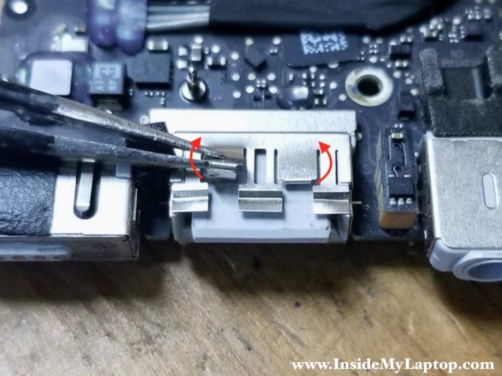 Bend damaged USB port grounding strips upwards using needle nose tweezers.