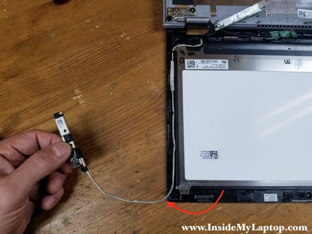 Un-route the webcam cable from the guided path on the side of the display assembly.