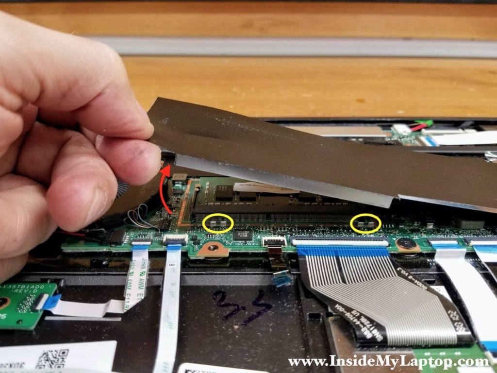 Carefully pull the mylar sheet up to separate the metal cover from the clamps on the motherboard.